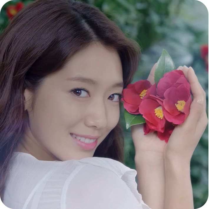 제품 원료인 동백꽃을 들고 웃고 있는 모델컷