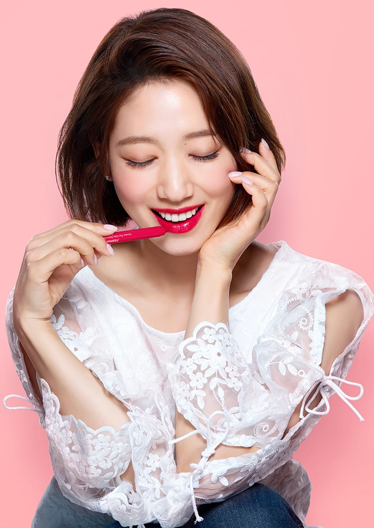 크리미 틴트 컬러 밤 글라이드를 입술에 바르고 제품을 들고 있는 모델